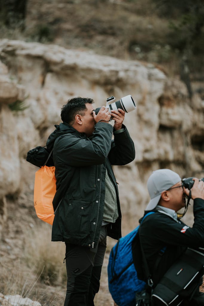 Two photographers taking pictures in a rugged rocky valley, showcasing adventure and exploration.